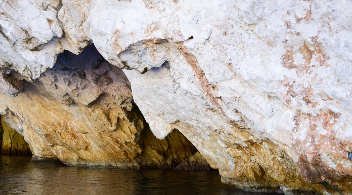 Close view of weathered white and ochre limestone showing deep erosion channels and overhangs